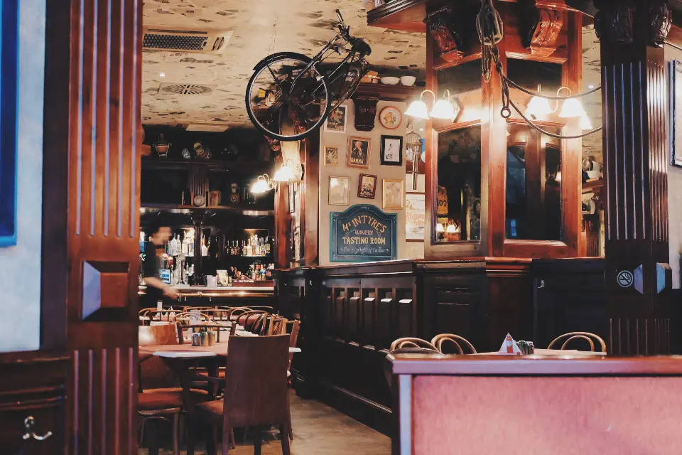 Šank restorana s drvenim policama i toplim svjetlom.